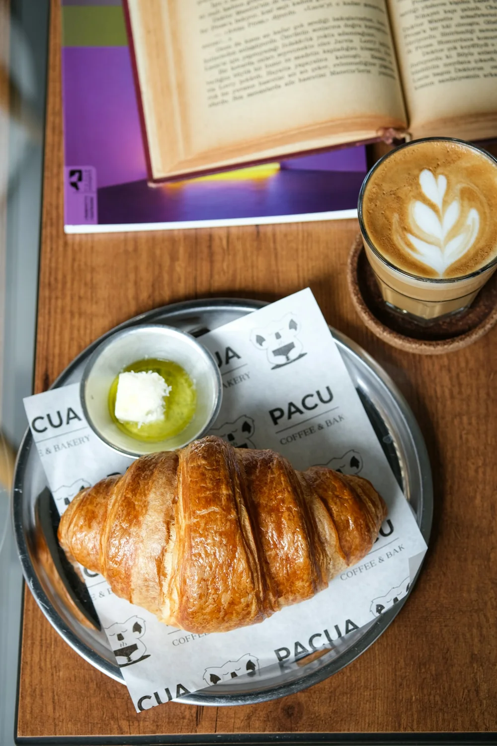 Croissant, butter and coffee on a wooden cafe table