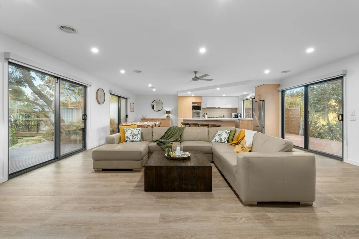 Open contemporary living room with neutral furniture and broad glass doors